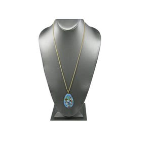 Puede incluir: Un collar de cadena dorada con un colgante azul. El colgante tiene forma de l&aacute;grima y presenta un dise&ntilde;o de mosaico con piedras preciosas de colores. El collar se exhibe en un busto de joyer&iacute;a gris.
