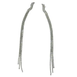 May include: A pair of silver-toned, dangling earrings. Each earring features a series of small, sparkling rhinestones arranged in a cascading, linear design. The earrings have a curved top and a long, flowing length, creating a glamorous and eye-catching accessory.