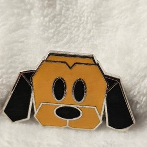 May include: A yellow and black origami-style pin of a dog with floppy ears. The dog has a black nose and black eyes.