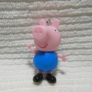 May include: A pink pig character with a blue shirt and black shoes. The pig has a small loop on the top of its head.