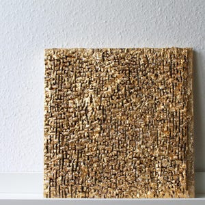 May include: A square gold textured wall art piece with a rough, uneven surface.