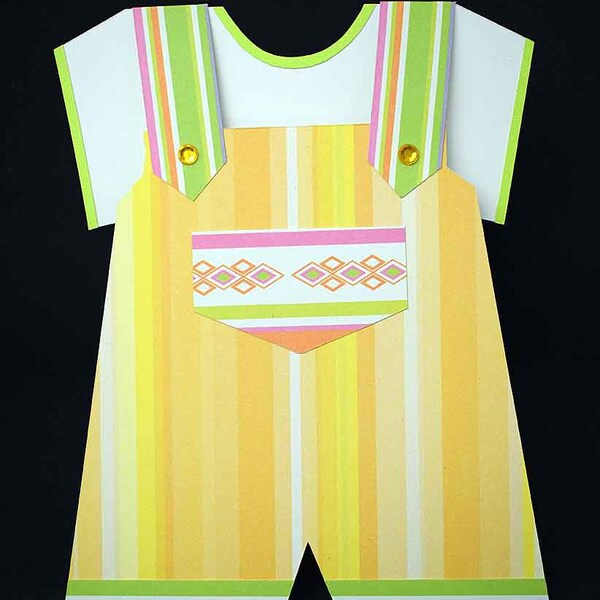 3D birth card on white paper and striped overalls in the shape of green orange yellow pink stripes