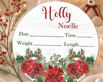 May include: A round white wooden sign with a faux wood grain texture featuring the red text Holly Noelle. Below the name are lines for Date, Time, Weight, and Length. The bottom is decorated with a watercolor illustration of red poinsettias.
