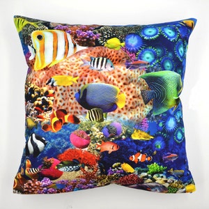 Peut inclure: Coussin carré avec un motif sous-marin vibrant. Le coussin présente des coraux colorés et diverses espèces de poissons, dont des poissons-clowns et des poissons-anges, sur un fond bleu profond. Le motif est imprimé sur la surface du coussin.