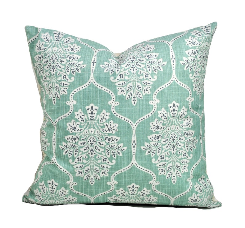 Pu&ograve; includere: Un cuscino quadrato decorativo con sfondo verde acqua chiaro e motivo floreale bianco e grigio scuro. Il cuscino ha un aspetto strutturato e un aspetto morbido e invitante, perfetto per aggiungere un tocco di eleganza a qualsiasi stanza.