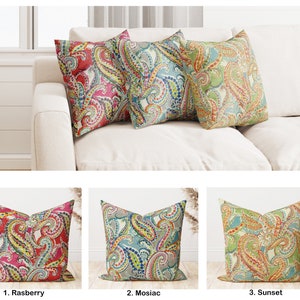 May include: Three decorative throw pillows with paisley patterns in different color combinations. The pillows are arranged on a white couch. The pillows are labeled 1. Raspberry, 2. Mosaic, and 3. Sunset.
