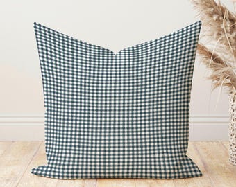 May include: A square cushion featuring a navy blue and white gingham check design. The cushion is made of fabric and has a soft appearance. It is positioned on a wooden floor, suitable for home decor.