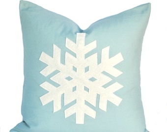May include: A light blue throw pillow with a white felt snowflake design.