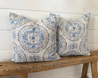 May include: Two decorative throw pillows with a blue and brown geometric pattern. The pillows are on a weathered wooden bench.