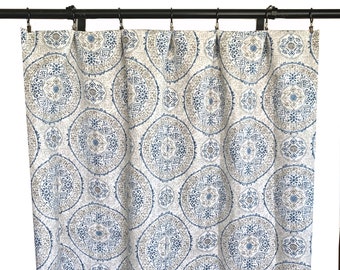 May include: A patterned curtain featuring a repeating circular design in blue, grey, and white. The curtain hangs from a black rod with metal rings. The fabric has a textured appearance.