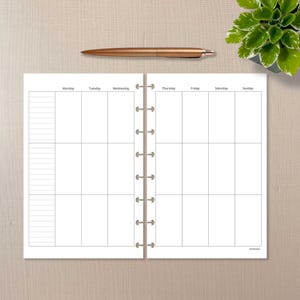 May include: Open planner with a weekly layout, featuring sections for each day of the week. A rose gold pen rests above the planner. A small potted plant is in the upper right corner. The planner is open to a blank page.