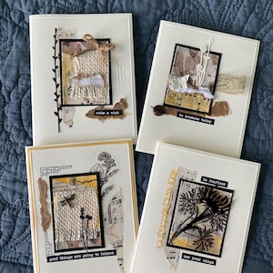 May include: Four handmade greeting cards with a collage design. Each card features a cream-colored background with a black framed central image, incorporating torn paper, fabric, and botanical elements. Text includes "make a wish", "be awesome today", "good things are going to happen", and "use your wings".