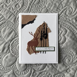 May include: A handmade wooden sign with the text "Welcome to our home" in a handwritten style. The sign is painted white with a dark stained wooden frame. A small green plant is placed on the sign.