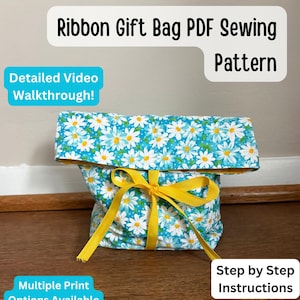 May include: A handmade gift bag with a blue daisy print, tied with a yellow ribbon. The bag is made from fabric and has a rolled-down top. Text on the image reads "Ribbon Gift Bag PDF Sewing Pattern", "Detailed Video Walkthrough!", "Multiple Print Options Available", and "Step by Step Instructions".