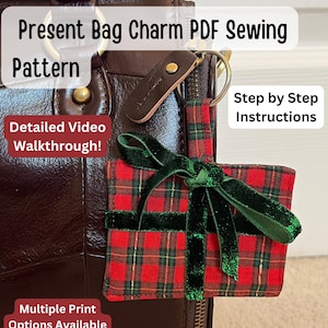 May include: A red and green tartan present-shaped bag charm with a green velvet ribbon. The charm is attached to a brown leather keychain. Text on the image reads "Present Bag Charm PDF Sewing Pattern", "Detailed Video Walkthrough!", "Step by Step Instructions", and "Multiple Print Options Available".