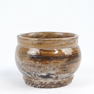May include: A handcrafted ceramic pot with a rustic, earthy aesthetic. The pot features a rounded body and a slightly flared rim. The exterior showcases a blend of brown and tan hues, with visible brushstrokes and a textured surface.