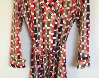 May include: A long-sleeved robe with a geometric pattern in shades of brown, red, white, and black. The robe has a collar and a tie belt. The label on the robe reads "Harrods".