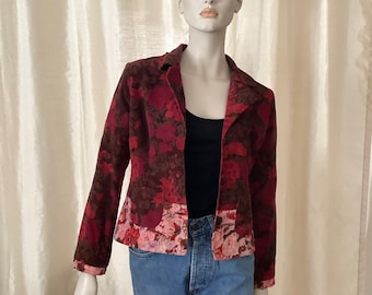 May include: A red and pink floral print cropped jacket with a black collar and long sleeves.
