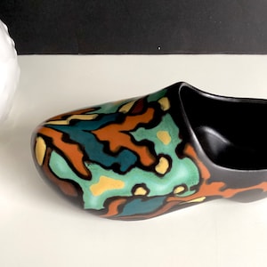 May include: A black ceramic shoe-shaped planter with a colorful abstract design in shades of green, blue, orange, and yellow.