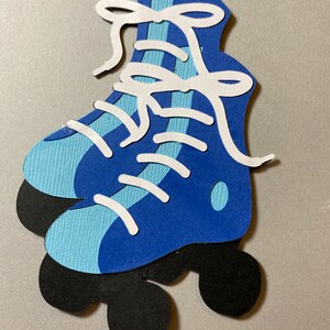 May include: Blue and white roller skates with black wheels. The skates have white laces and a blue and white striped pattern.
