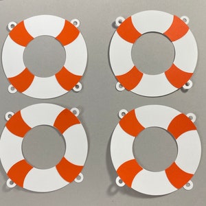 May include: Four white paper life preserver cutouts with orange stripes. Each life preserver has three holes punched around the edge.