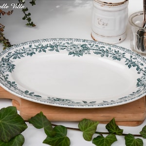 Peut inclure: Un plat de service ovale blanc avec un motif floral vert. Le plat est sur une planche à découper en bois.