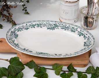 May include: A white oval serving platter with a green floral design. The platter is on a wooden cutting board.