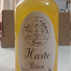 May include: A clear bottle of yellow liquid soap with a white cap. The label reads "Pure Alchemy Soaps" and "Haste Potion Liquid Soap" in elegant script. The bottle is approximately 8 inches tall.