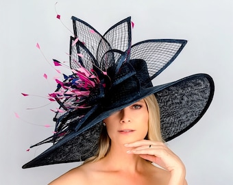 Può includere: Un grande cappello blu navy con un'ampia tesa e un drammatico design di piume rosa e blu a più livelli. Il cappello è indossato da una persona con i capelli biondi.
