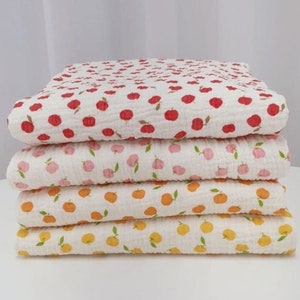 Peut inclure: Un ensemble de quatre carrés de tissu en coton blanc avec différents motifs de fruits. Le carré du haut a des pommes rouges, le deuxième a des pommes roses, le troisième a des oranges orange et le dernier a des citrons jaunes.
