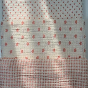 May include: Three pieces of fabric with different patterns. The top piece has small pink dots on a white background. The middle piece has small pink hearts on a white background. The bottom piece has a pink and white gingham pattern.