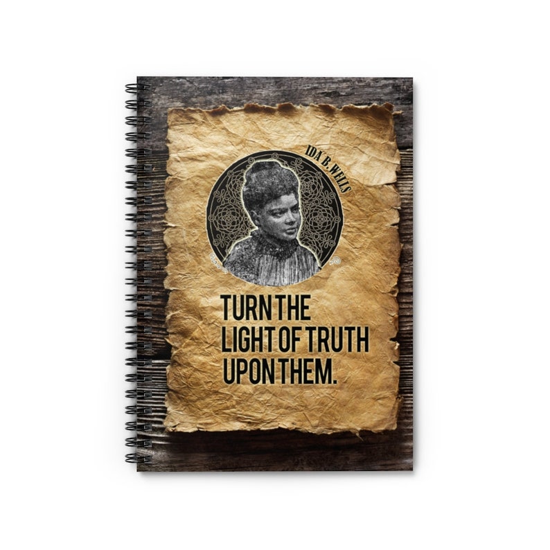 May include: A spiral bound notebook with a wood grain background and a vintage paper overlay. The paper features a black and white portrait of Ida B. Wells with the text "IDA B. WELLS" above her portrait and "TURN THE LIGHT OF TRUTH UPON THEM." below her portrait.