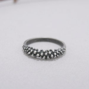 Op de afbeelding: Een zilveren ring met een getextureerde band van kleine, verhoogde stippen.