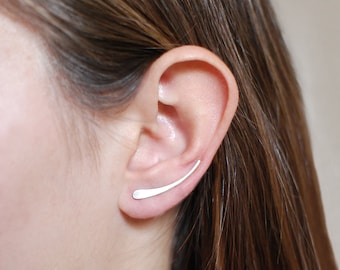 May include: A silver ear cuff earring with a curved design. The earring is worn in the upper part of the ear.