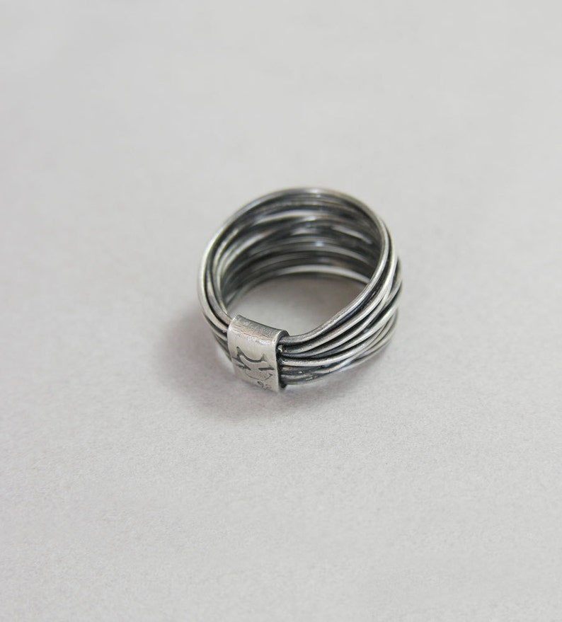 May include: A silver ring with multiple bands stacked on top of each other. The ring is marked with the number "11".