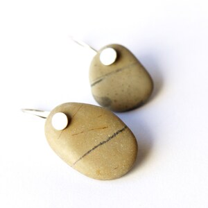 May include: A pair of silver earrings with a natural stone pendant. Each stone is a different shape and has a unique pattern. The stones are a light brown color with dark brown and black streaks.