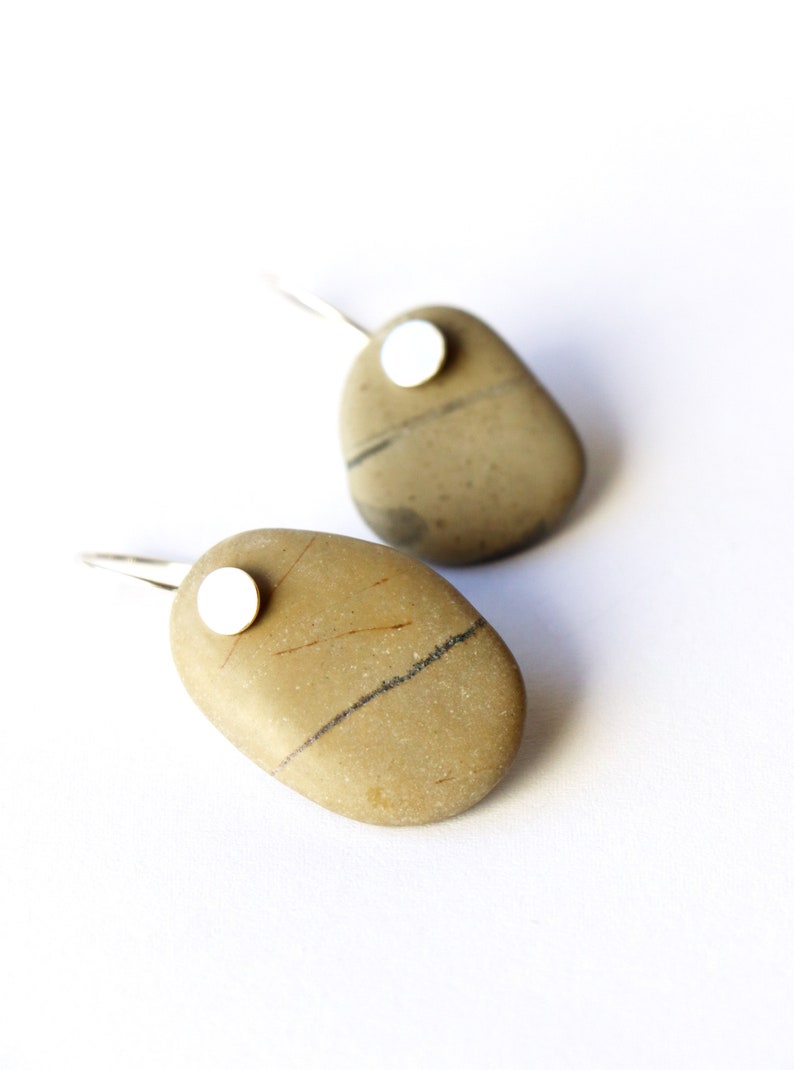 May include: A pair of silver earrings with a natural stone pendant. Each stone is a different shape and has a unique pattern. The stones are a light brown color with dark brown and black streaks.