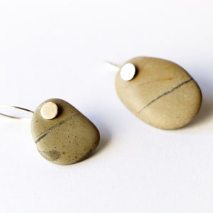 May include: A pair of earrings made from natural stones with a silver accent. The stones are a light brown color with dark brown streaks.