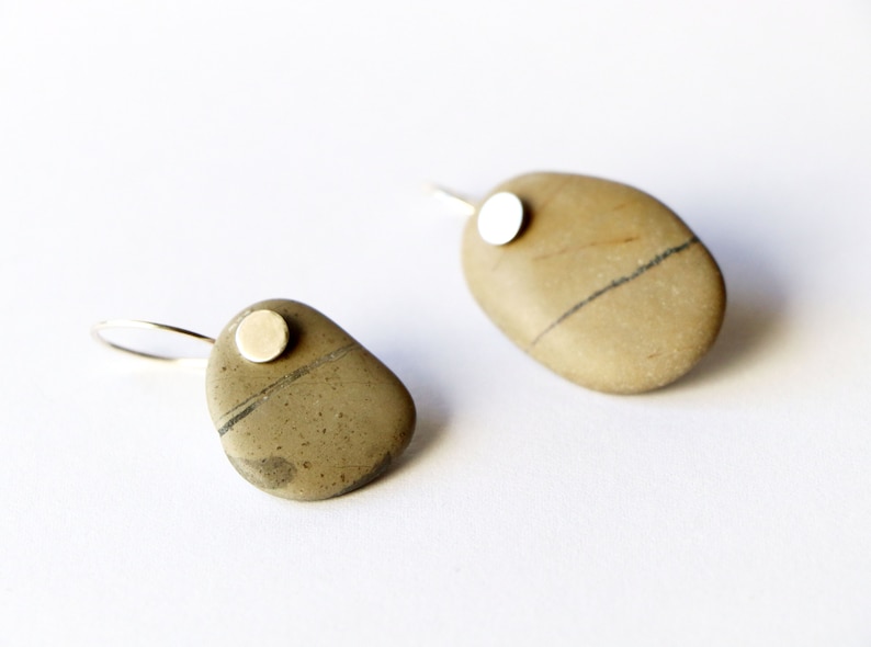 May include: A pair of earrings made from natural stones with a silver accent. The stones are a light brown color with dark brown streaks.