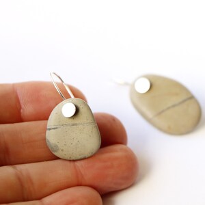 May include: A pair of silver hoop earrings with a natural stone pendant. Each stone is a different shape and has a silver disc attached to the top.