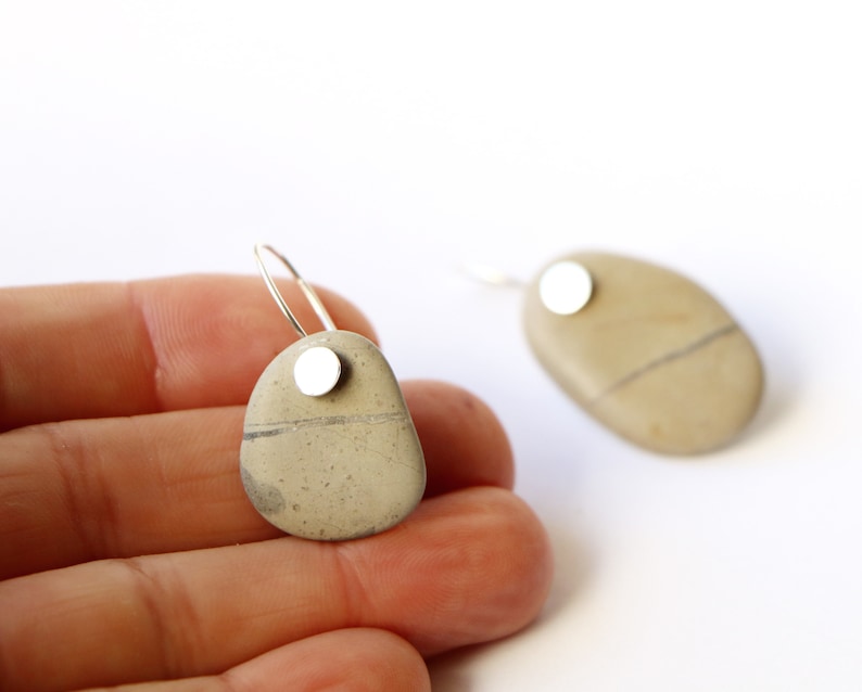 May include: A pair of silver hoop earrings with a natural stone pendant. Each stone is a different shape and has a silver disc attached to the top.