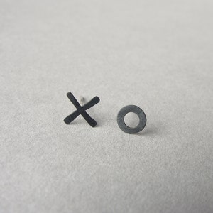 May include: A pair of black metal earrings, one shaped like an 'X' and the other a circle.
