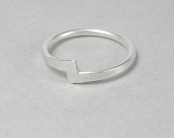 May include: A silver ring with a geometric design. The ring is simple and modern.