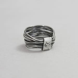 May include: A silver ring made of multiple thin bands twisted together. The ring is marked with "925" on the side.