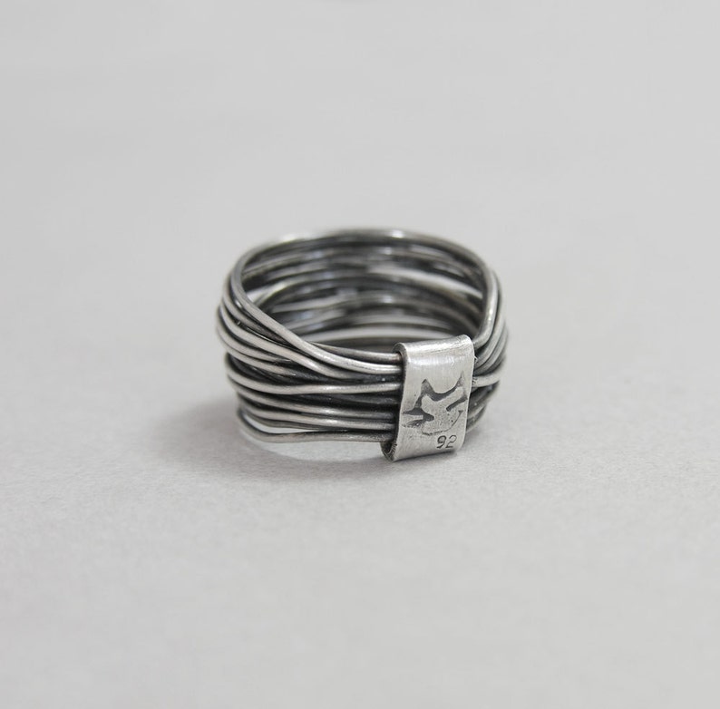 May include: A silver ring made of multiple thin bands twisted together. The ring is marked with "925" on the side.