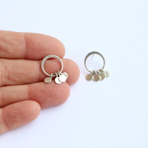 Peut inclure: Une paire de boucles d'oreilles créoles en argent avec de petits cercles en argent qui pendent en dessous.