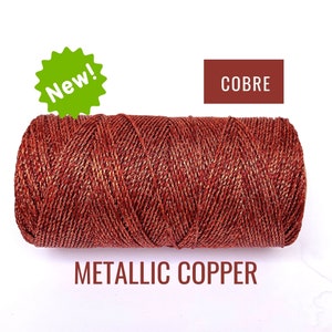 May include: A spool of metallic copper cord with a red and gold color. The spool is labeled "COBRE" and "METALLIC COPPER".