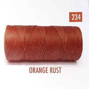 May include: A spool of orange rust colored waxed thread. The spool is labeled with the number 234 and the color name "ORANGE RUST".