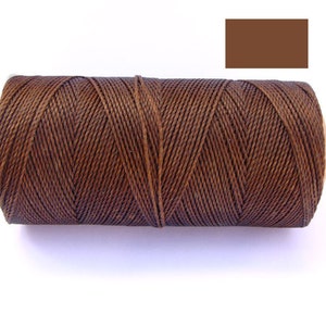 Puede incluir: Una bobina de hilo encerado marrón para la elaboración de cuero.