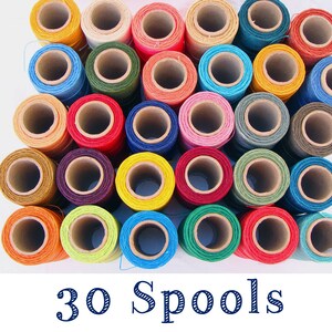 May include: Thirty spools of colorful thread, arranged in a circular pattern. The spools are made of cardboard and have a variety of colors, including red, blue, green, yellow, and orange.